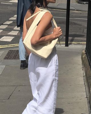 Woman wears white linen trousers and carries yellow handbag