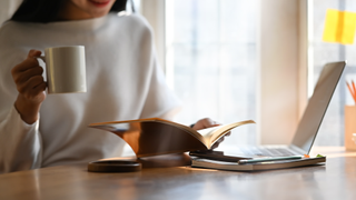 Woman reading book while drinking hot drink