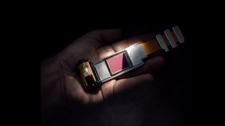 A hand holding the upcoming I'm Back APS-C sensor that fits into a film-shaped device