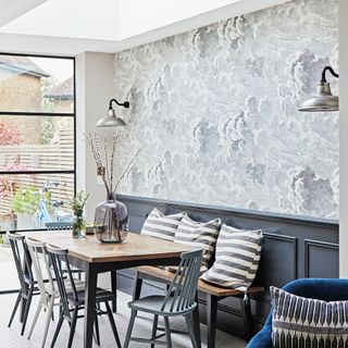 Dining room with grey cloud wallpaper above dado rail by floor to ceiling windows