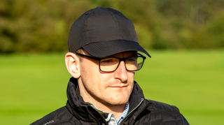 A golfer poses wearing the Zero Restriction Baseball Cap in black