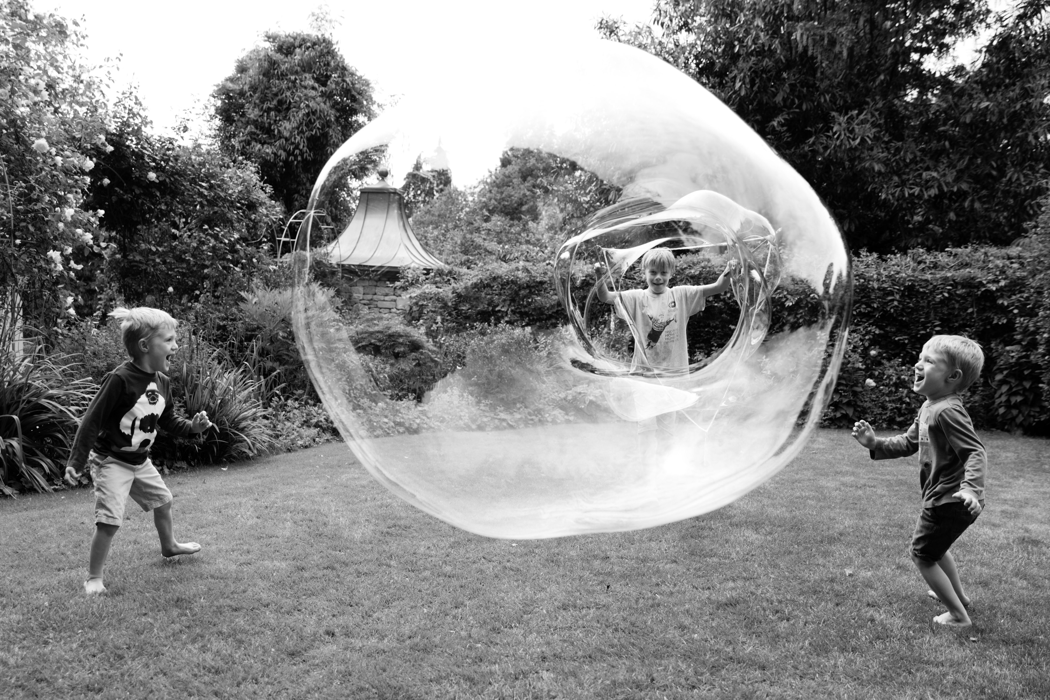 Photograph of two children playing either side of a large bubble, taken by family photographer Helen Bartlett, one of the speakers on the Canon Spotlight stage at The Photography &amp;amp; Video Show 2026