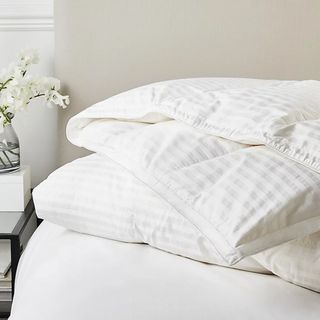 A duvet with a pinstriped cover on a white bed