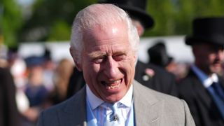 King Charles III speaks to guests attending a Royal Garden Party at Buckingham Palace