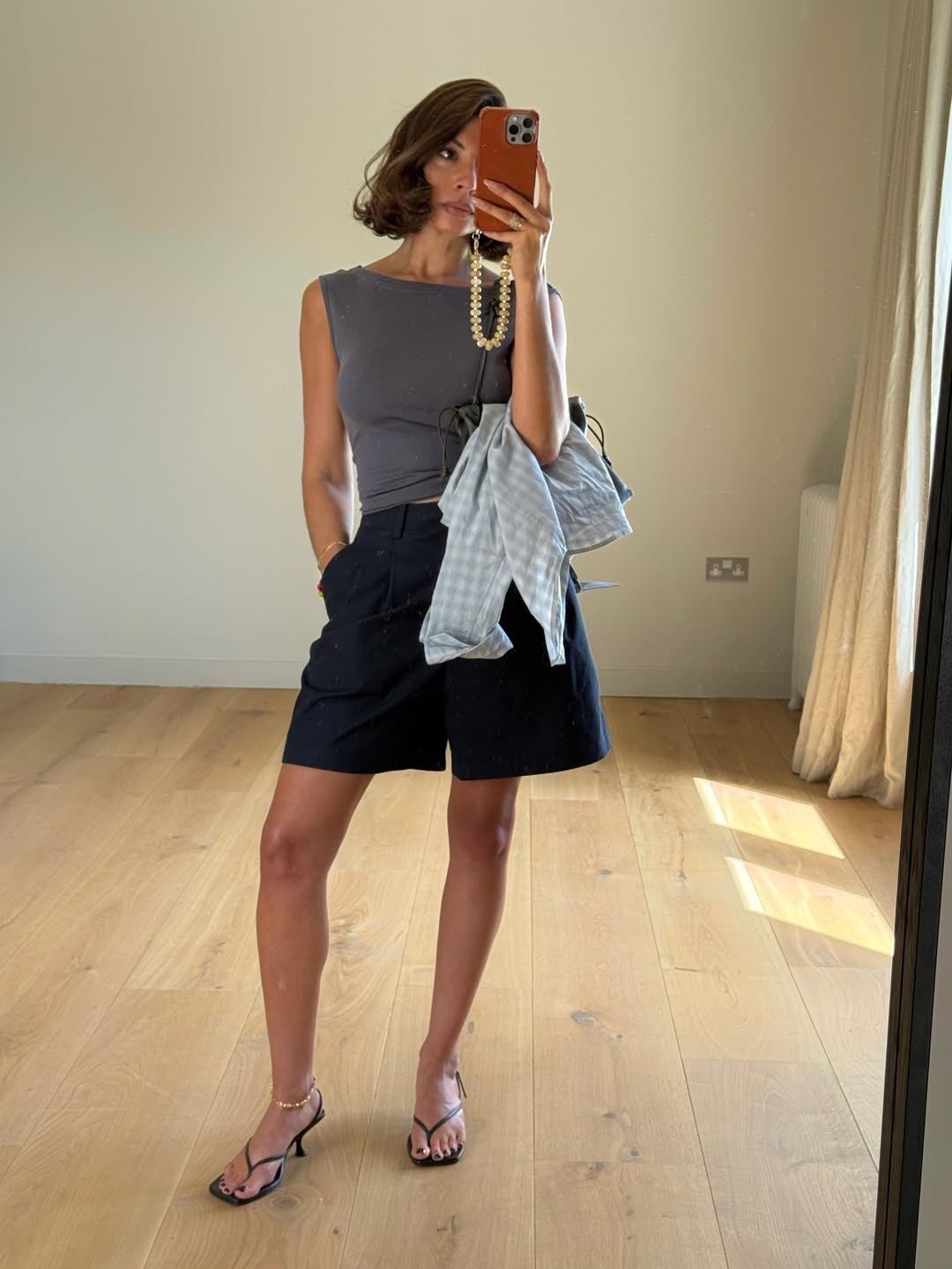 A woman taking a mirror selfie with a brunette bob hairstyle