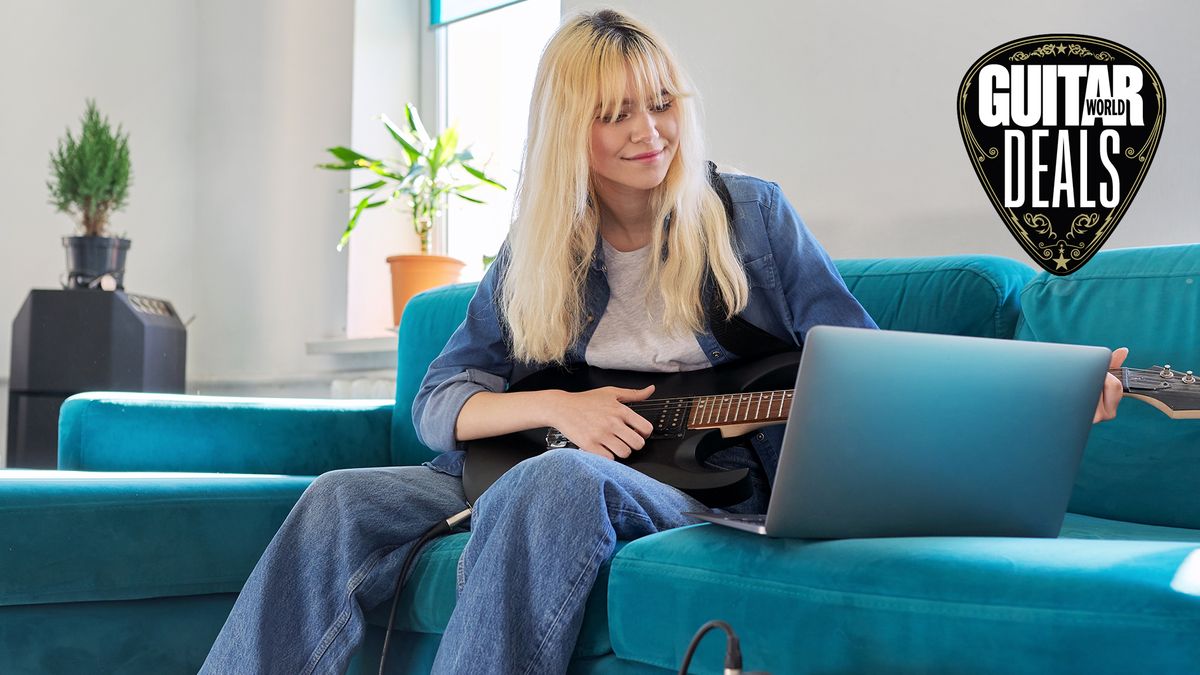 Woman plays her electric guitar in front of an open laptop