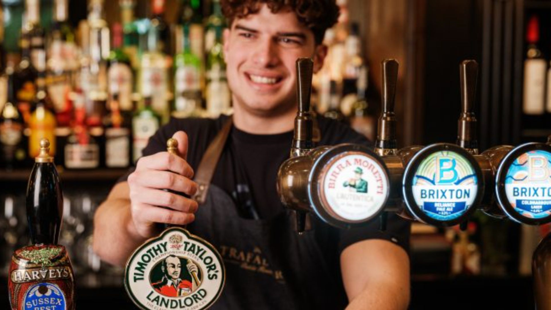 an image of a bartender pulling a pint behind the bar at one of the Three Cheers Co pubs