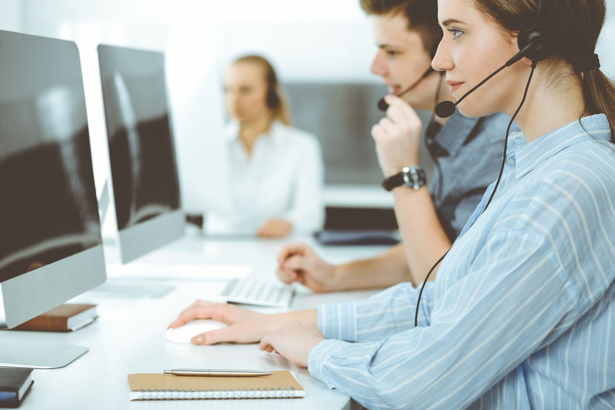 Call center employees on their headsets in front of computers