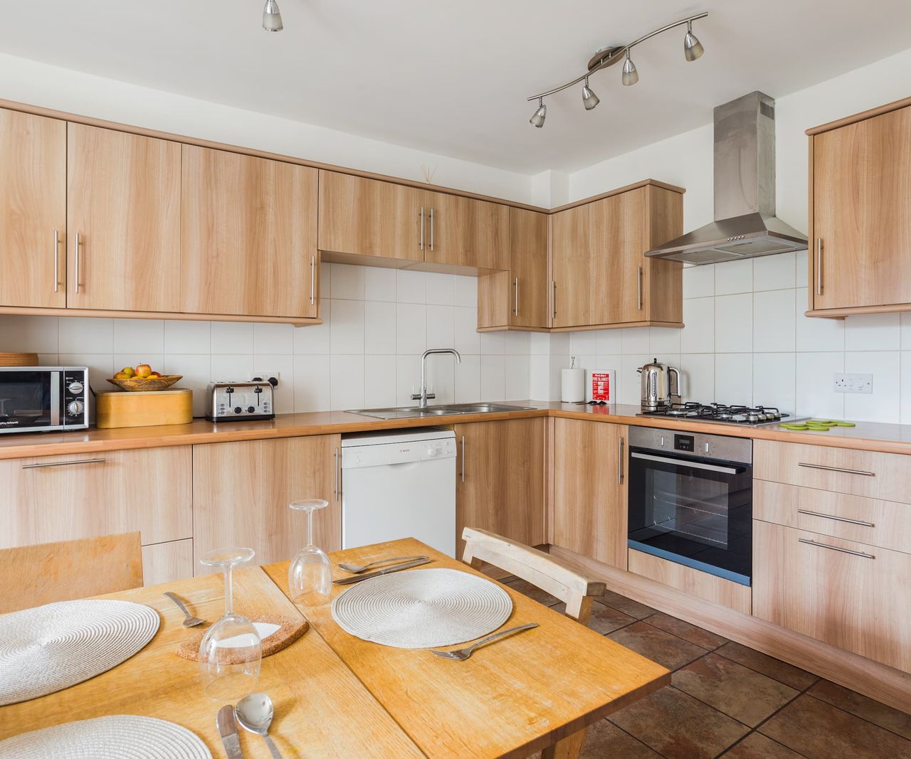 A kitchen with brown wooden cabinets and tiled floors