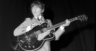 George Harrison, suited, booted, in the Fab Four's trademark mop-top hairstyle, plays a Gretsch live onstage in South Australia with the Beatles in 1964.