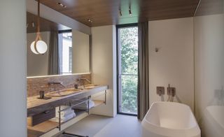 Bathroom with white stone bath and natural stone sinks and worktop