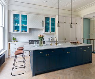 White and blue kitchen with white wall cabinets and a deep blue kitchen island