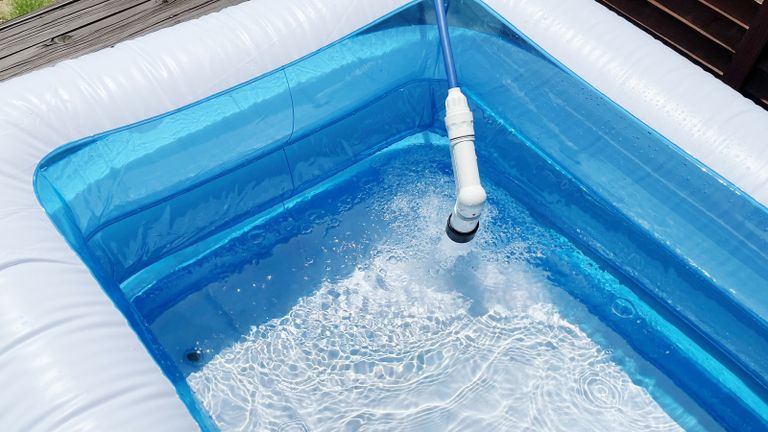 An inflatable swimming/paddling pool being filled with water outside on decked surface