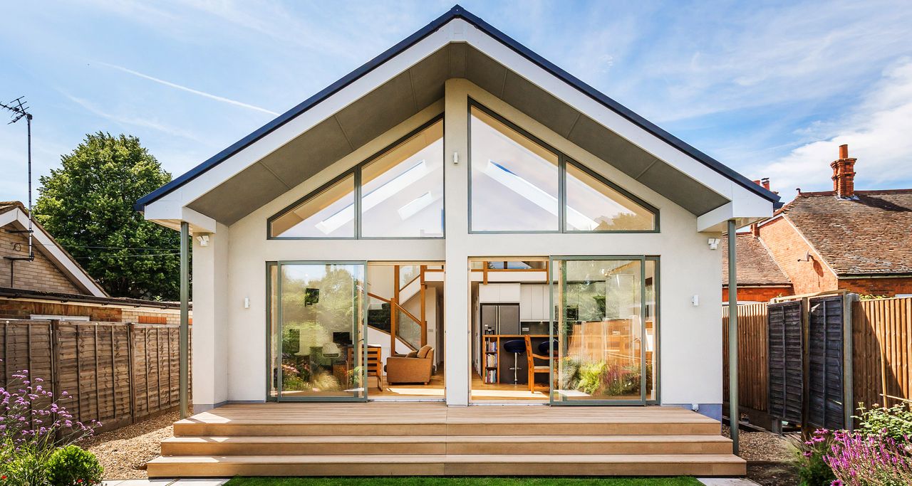 a modern house with white render and tall angular glazing 