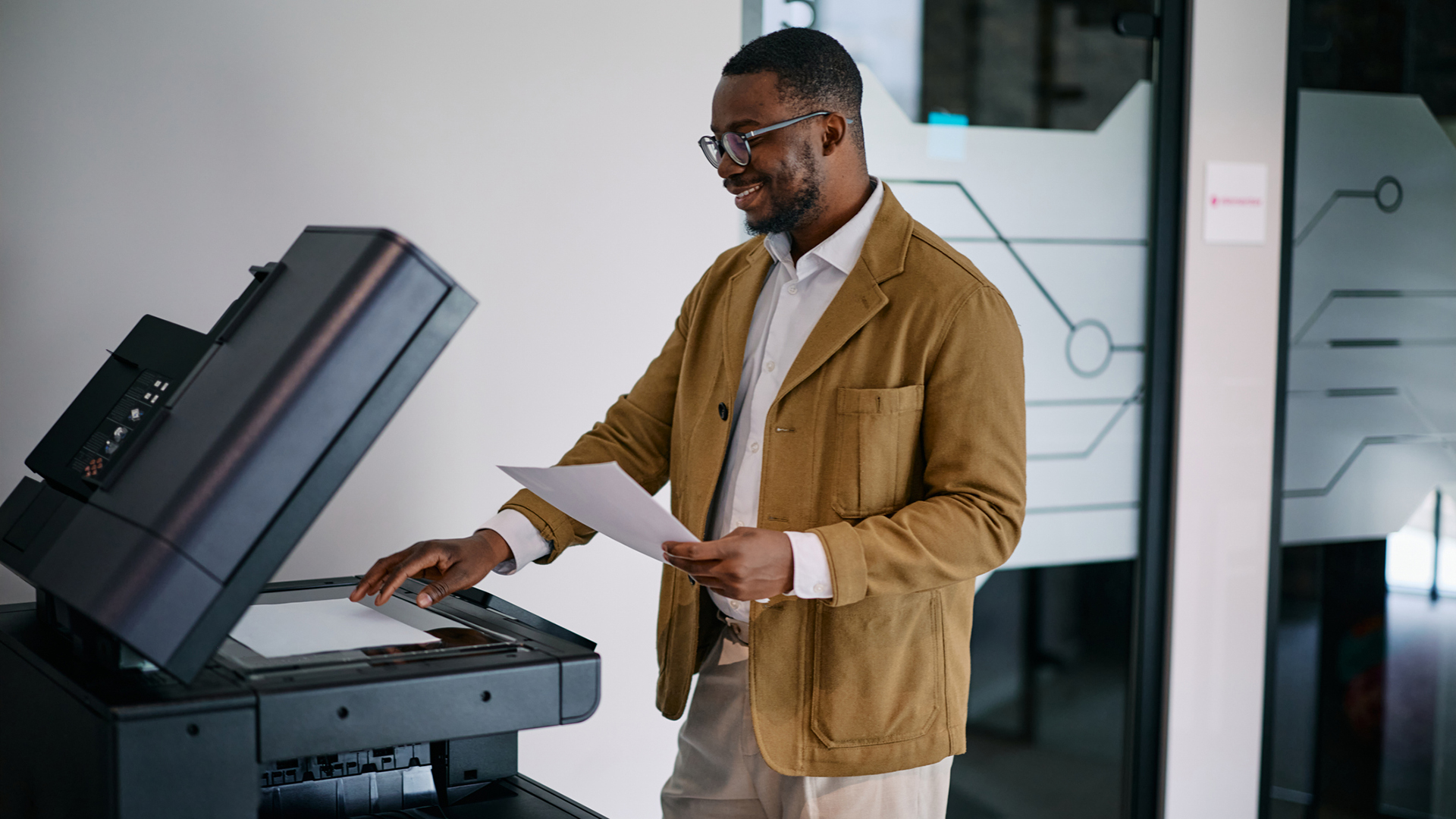 A photo of a businessman making a copy using a modern multifunction printer in an office.
