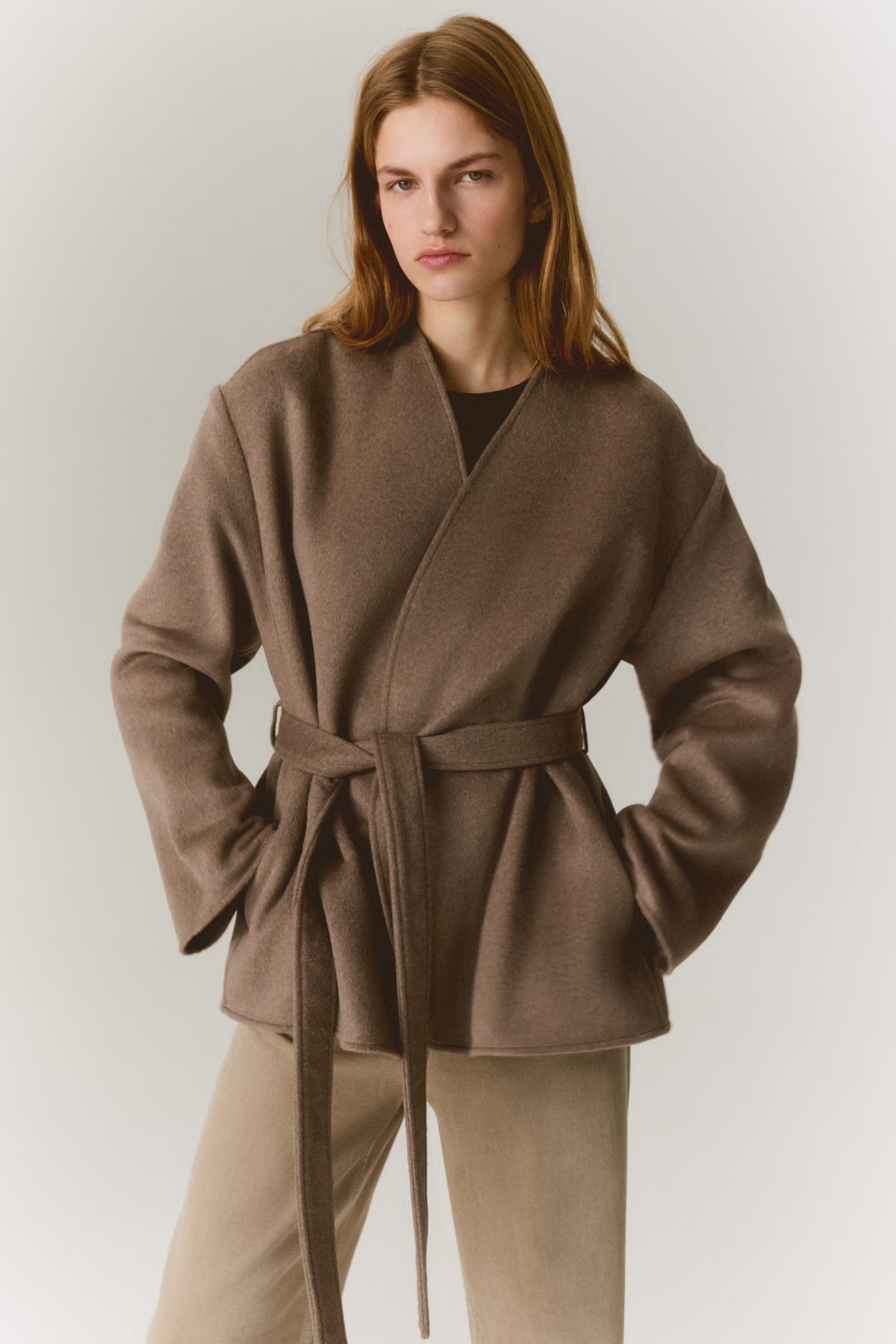 Woman wears brown wrap coat