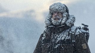 Man with furry in snowstorm with cloudy skies and snowflakes 