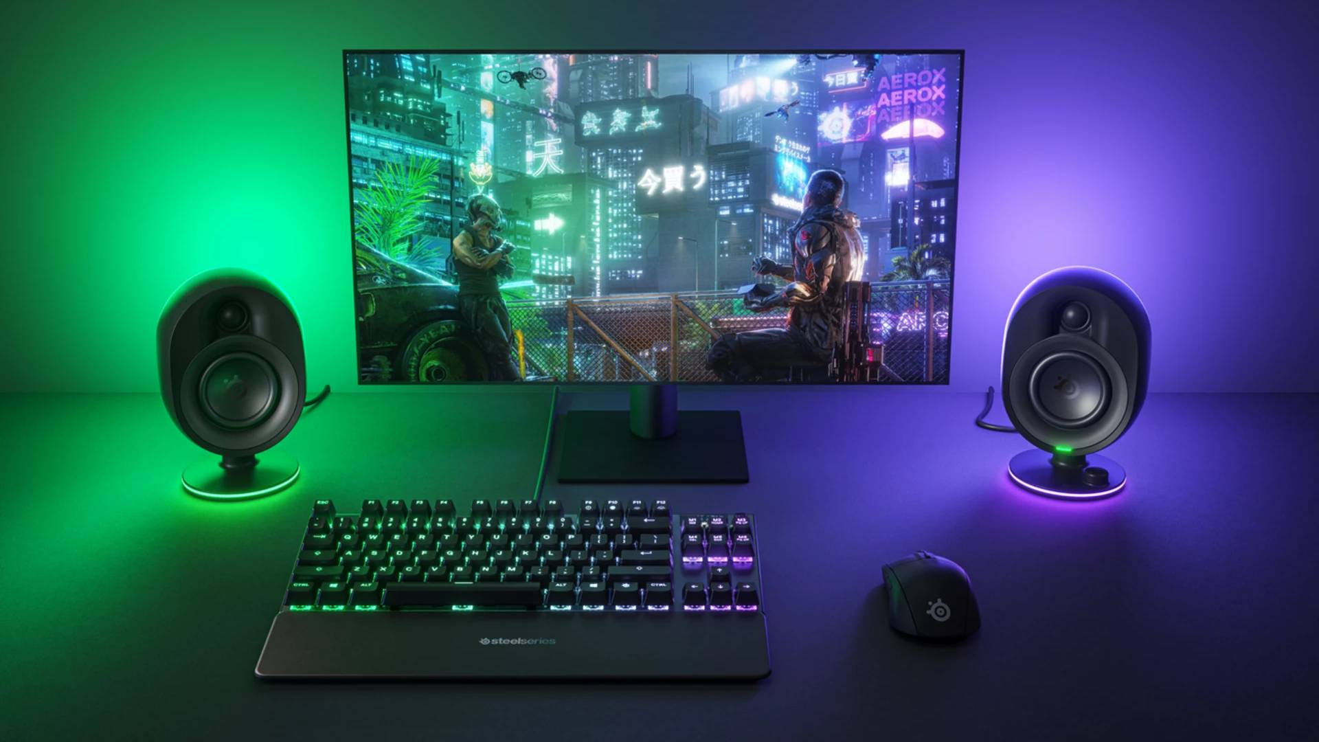 SteelSeries Arena speakers on desk with monitor, keyboard and mouse with RGB lighting in background