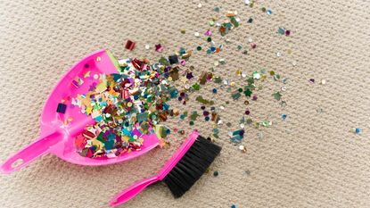 A dustpan and a broom clean up confetti after a party.