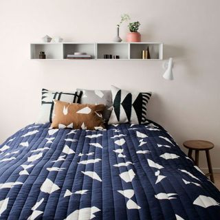 bedroom with blue and white bed linen with walled shelf