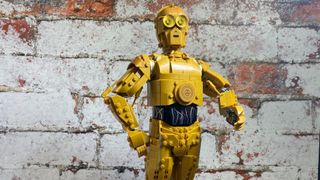 Lego C-3PO standing in front of a brick wall