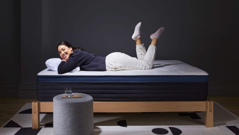 The image shows a woman in comfortable clothing laying on top of the Helix Midnight Luxe mattress