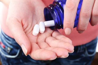 A woman pours calcium supplement pills into her hand