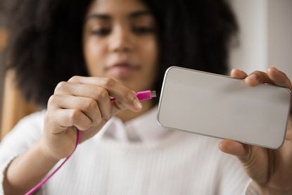Woman connecting cable to cell phone