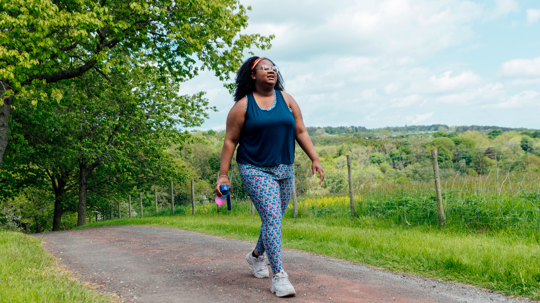 Woman walking outside with countryside in background