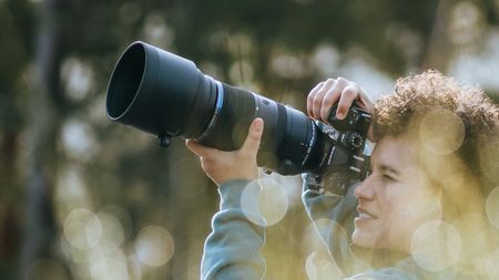 Photographer holding the OM System OM-1 II with M.Zuiko 150-600mm F5.0-6.3 IS lens attached