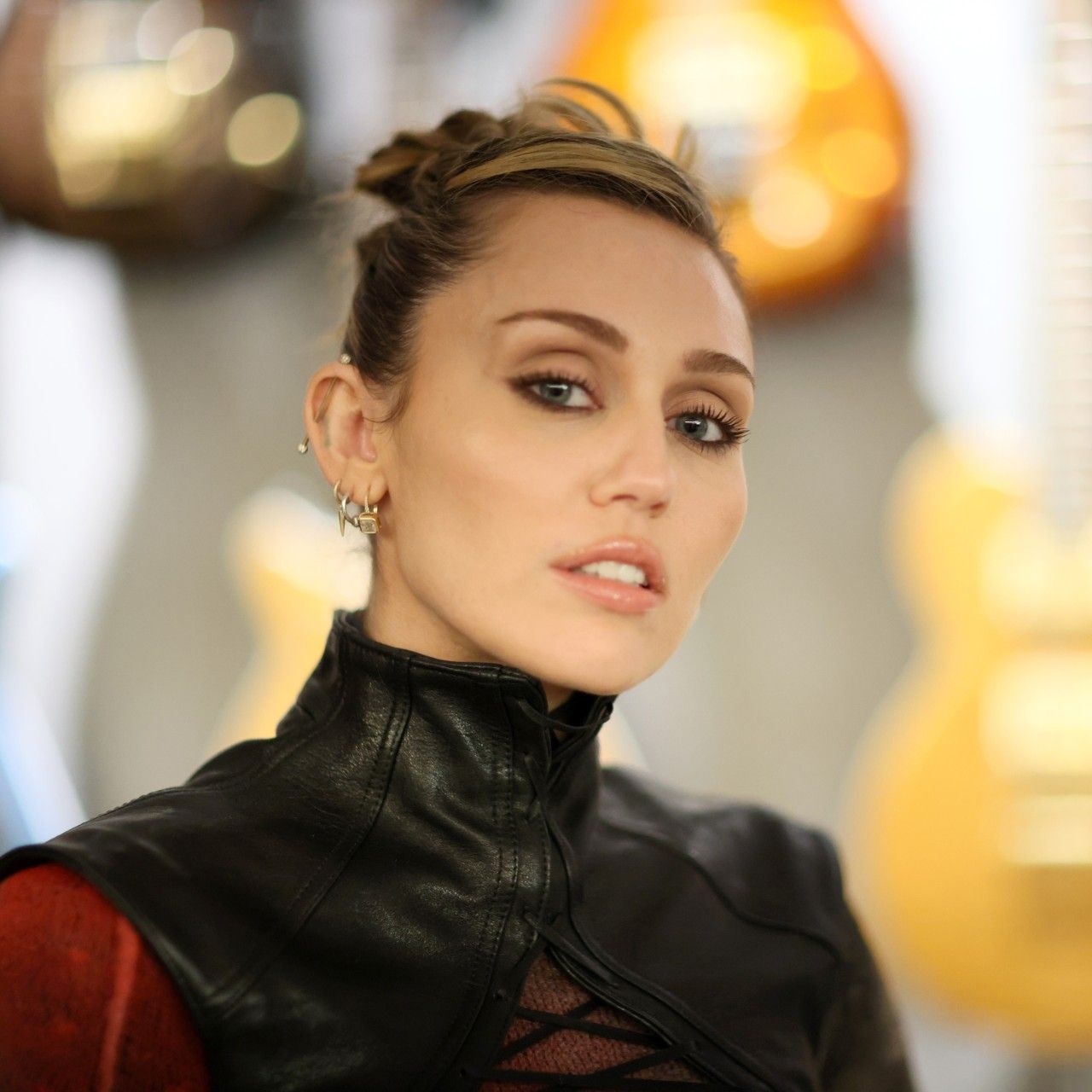 a white woman with blonde hair and dark eye makeup poses for a camera at an event