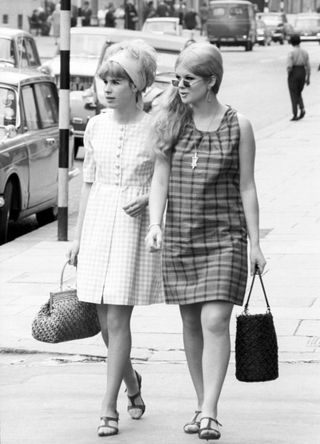 Two British girls in minidress walking in the street. London, 1960s