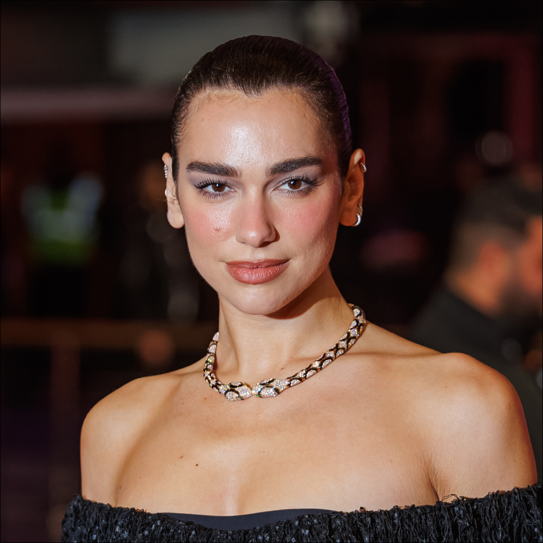 Dua Lipa wears an off-the-shoulder dress and wears her hair scraped back in a bun
