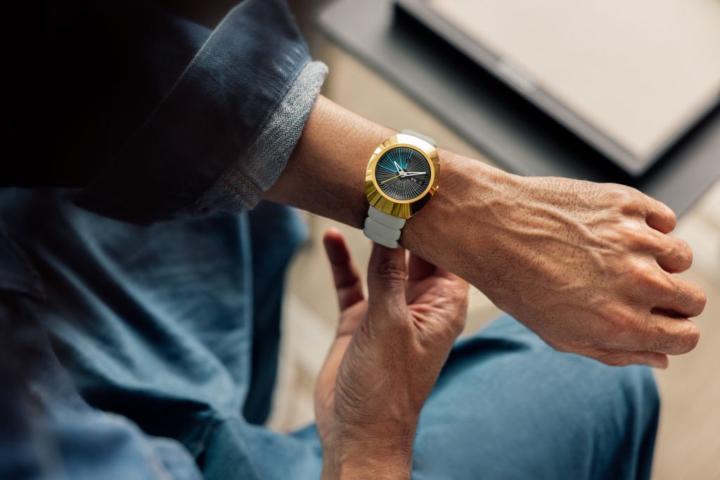 Wrist with a white watch with gold detailing