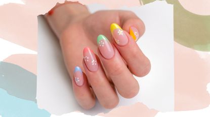 A hand with floral spring nail designs on a pink backdrop 