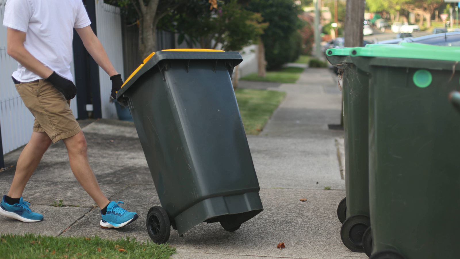 Person wheeling a bin near to two other bins
