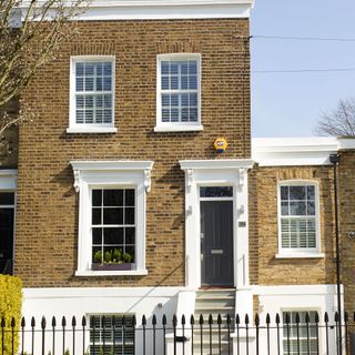 bricked exterior of house with dark front door and railings