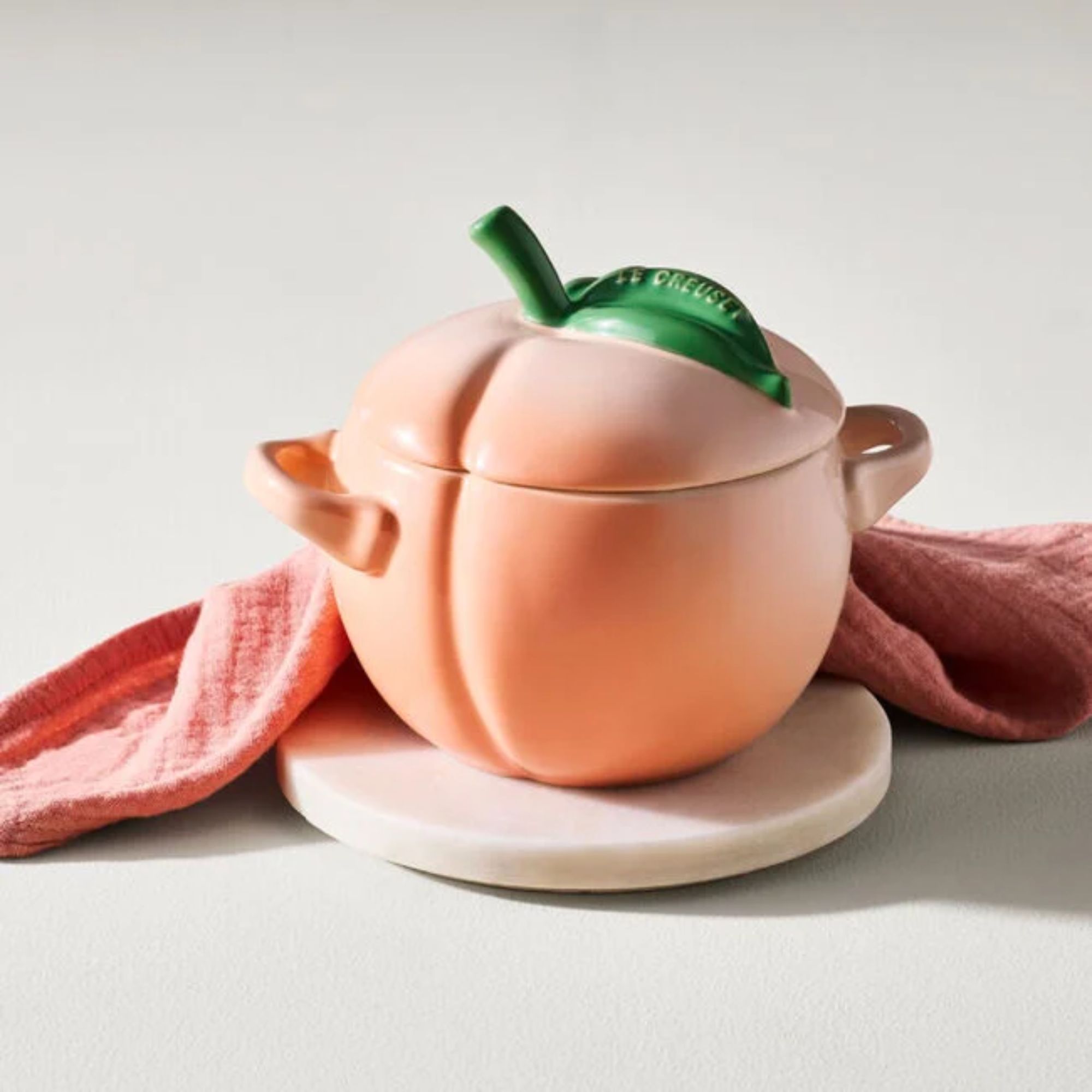 A Le Creuset mini cocotte shaped like a peach