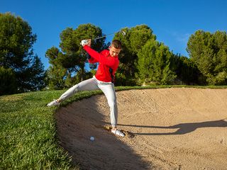 Alex Elliott playing a bunker shot at the back edge of the bunker