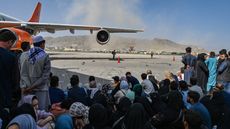 Afghan people sit as they wait to leave Kabul airport 