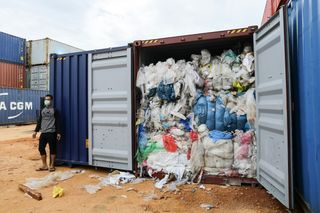 A man stands next to one of 65 containers full of imported plastic trash being inspected by the local environment office at the Batu Ampar port in Batam, Indonesia, on June 15, 2019.