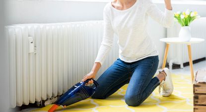 Woman at home wearing headphones hoovering the floor - stock photo