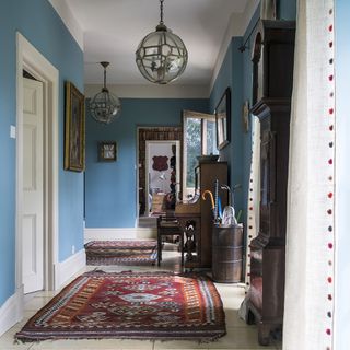 hallway with blue wall and tiles floor and rug
