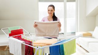 A woman hanging clothes on a drying rack