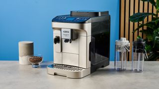 the de'longhi magnifica duo photographed with the blue tom's guide background showing the milk carafe and coffee machine screen