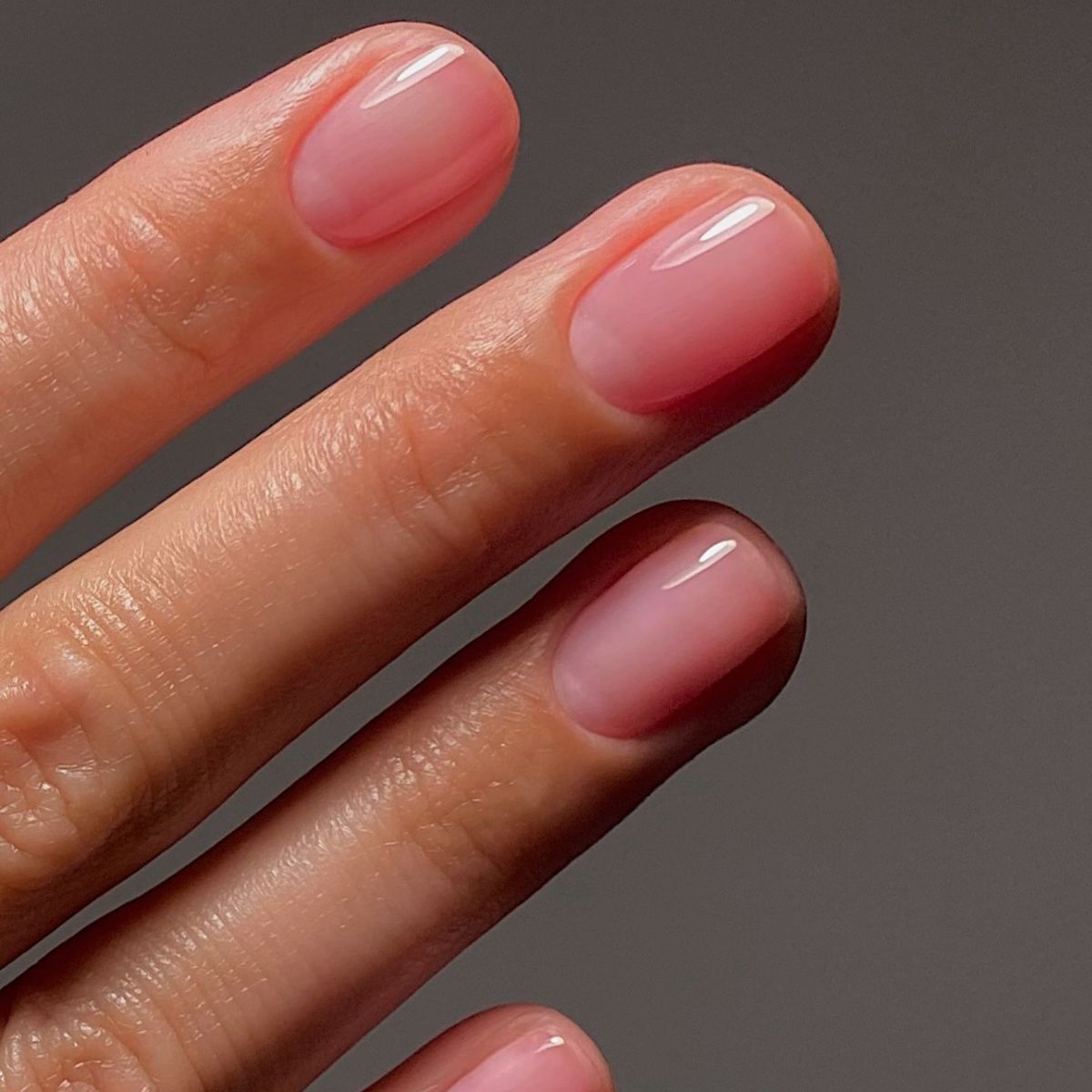 A picture of the grape manicure trend, showing a sheer pink nail polish on short nails