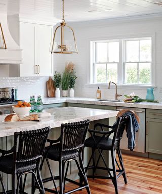 Pale green/gray kitchen wieth marble tops and an island