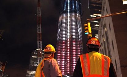 Construction workers look up at the Freedom Tower at the World Trade Center that is patriotically lit in advance of the tenth anniversary.