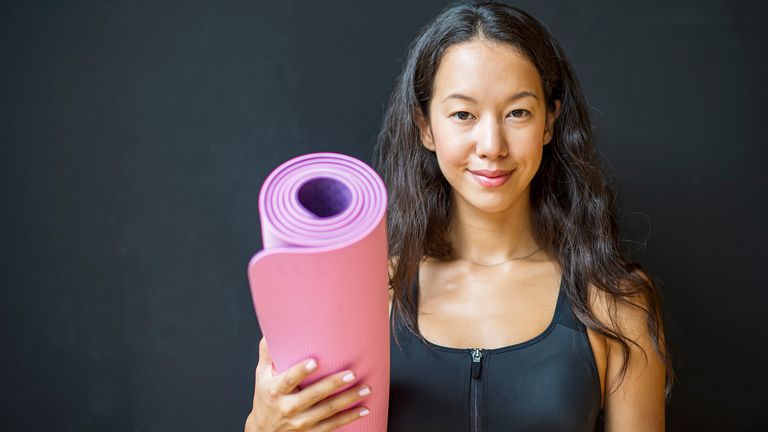 Smiling woman holding a Pilates mat