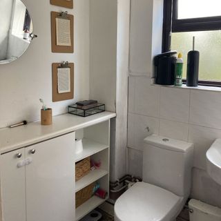 bathroom with round mirror and toilet seat and shelves
